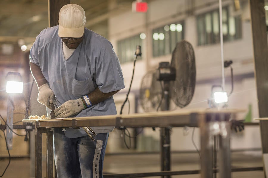 An inmate crafts a board of hardwood flooring.