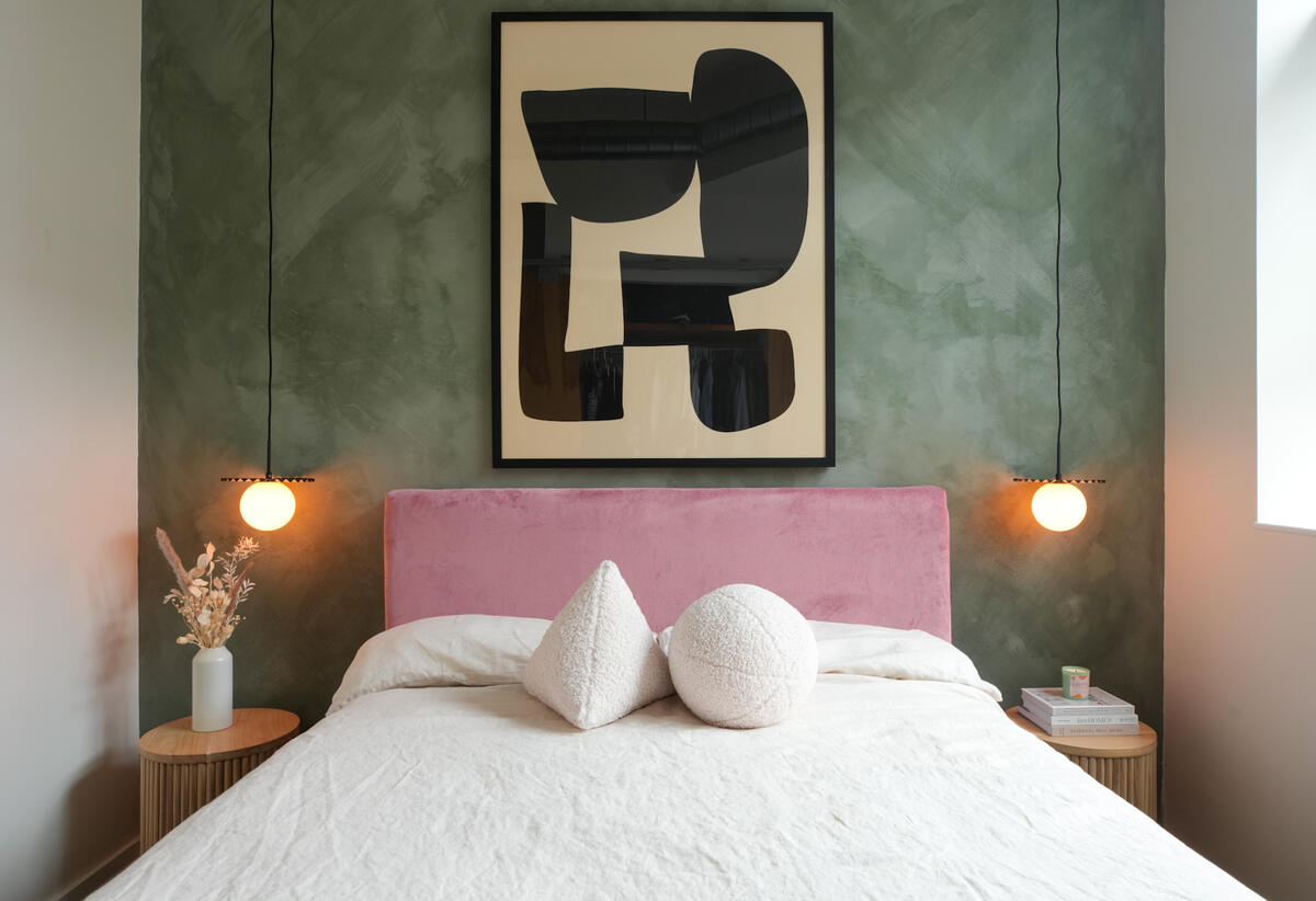 A bedroom with a bubblegum pink bed frame pops agains a textured wall