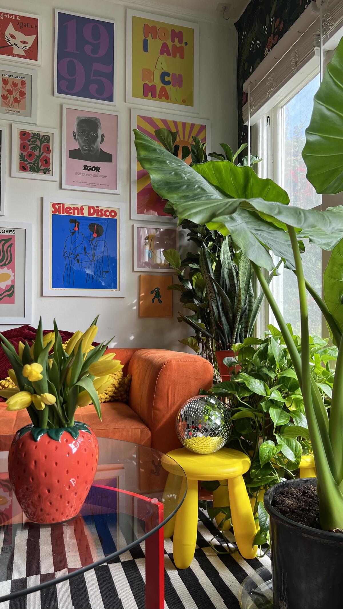 A colorful corner of Browning’s home boasting an orange couch and colorful gallery wall