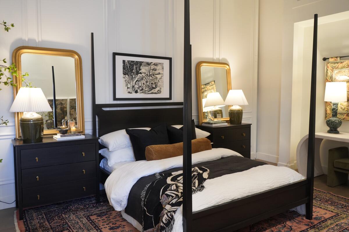 Brass mirrors lie on the dual nightstands in this black and white bedroom