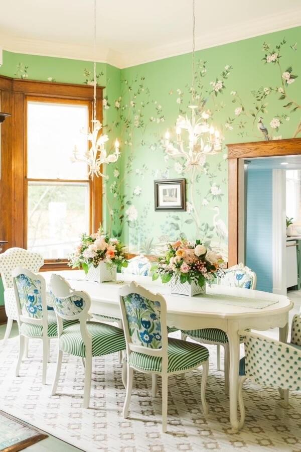 Chinoiserie wallpaper in a cheerful green envelops a sophisticated dining room