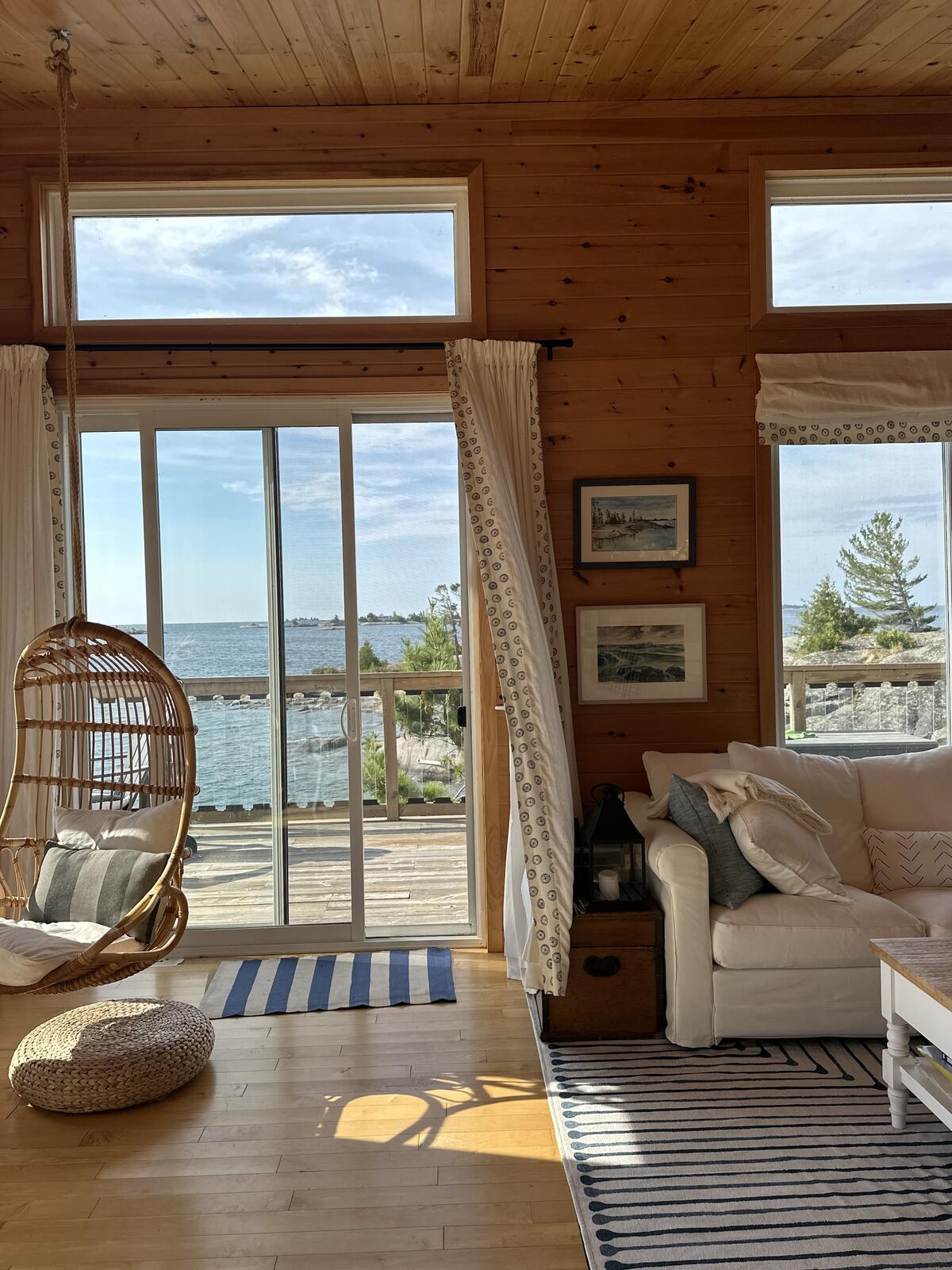 A wood paneled room that overlooks the water exudes a coastal cool 