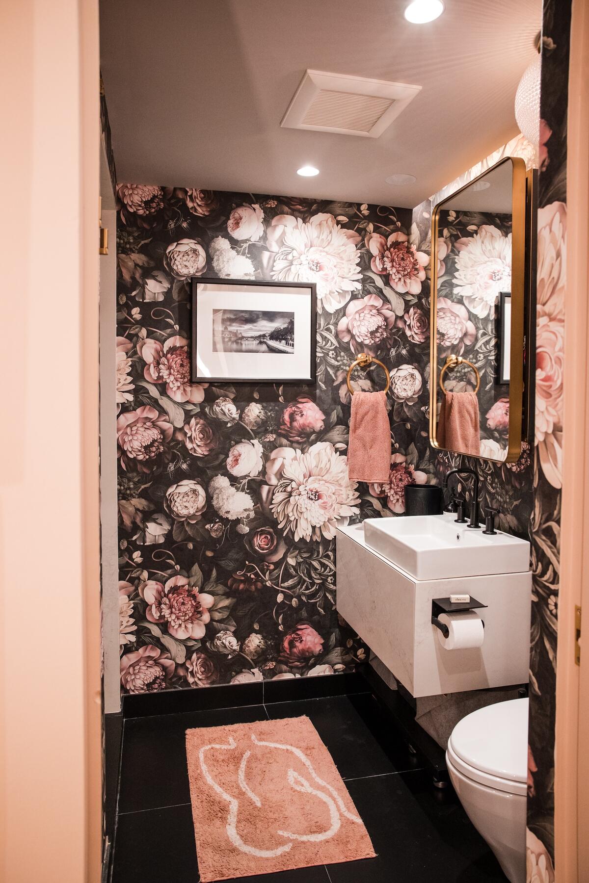 A powder room clad in moody floral wallpaper