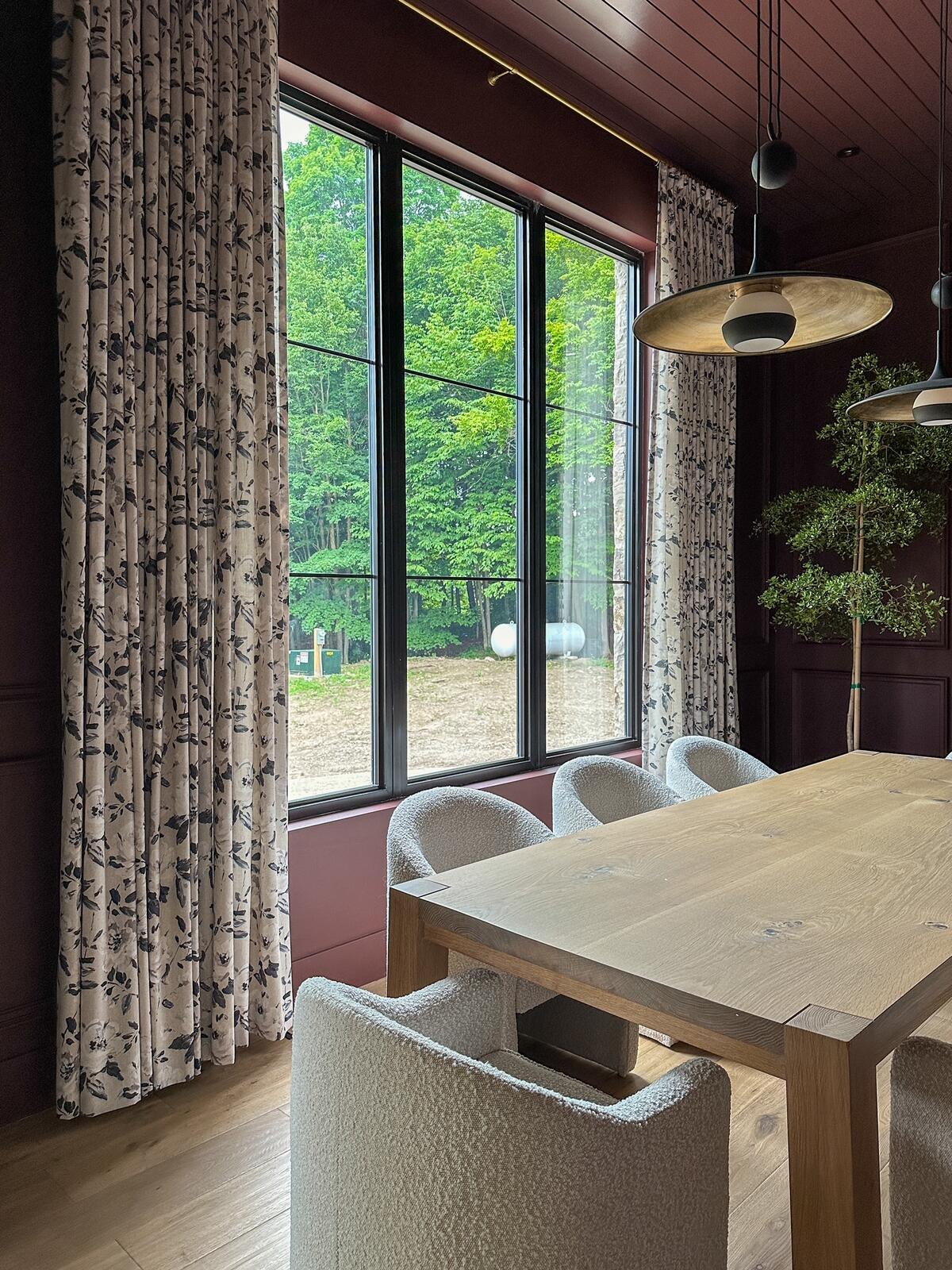 Bouclé dining chairs and walls swathed in a rosy hue create a cozy scene in this dining room