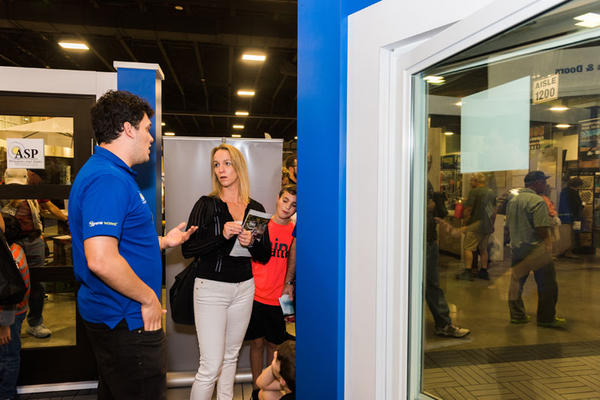 An exhibitor and attendee discuss windows. 