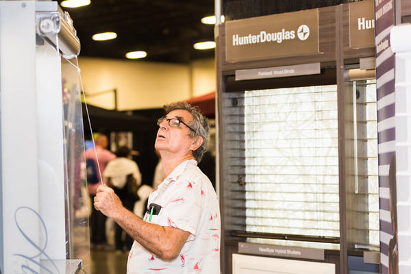 An attendee gets hands-on with a Hunter Douglas display.
