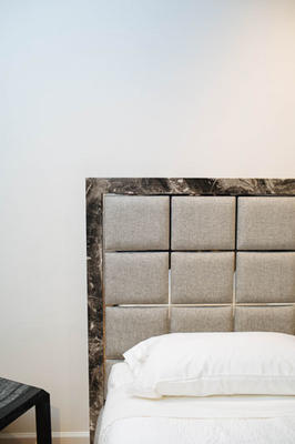 A windowpane bed made with an Arabescato marble frame, polished steel gridwork and upholstered panels