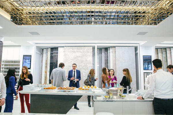 Press guests and Fiandre executives mingling in the Fiandre showroom centered by a gold glam mirror ceiling.