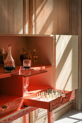 This liquor cabinet is truly a showcase for precious bottles. It is a creation of contrasting colors and textures, from the elegant finesse of the figured sycamore to the sleek look of the coral base. The piece also features bronze details from the Rinck collections, reworked to reveal the face of Hebe, Greek goddess of youth and cupbearer to the gods of Olympus. 