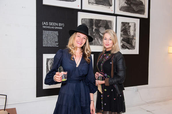 Abby Brammell and Johanna Sherry in front of charcoal drawings by Nicholas Grassi