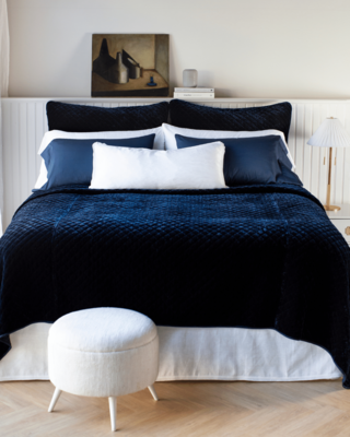 Bria pillowcases in White and Midnight with Bria flat sheet in White. Silk velvet quilted coverlet and shams in Midnight accented with Paloma lumbar pillow in White. 