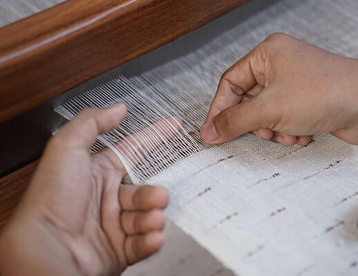 Fungi woven-to-size grass-weave window covering on the loom. Hand-placed mendong flowers are inserted into the weft of the material.