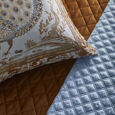 Divani Peacock pillow atop a Velvet coverlet in Amber and Double Diamond coverlet in Sky Blue 