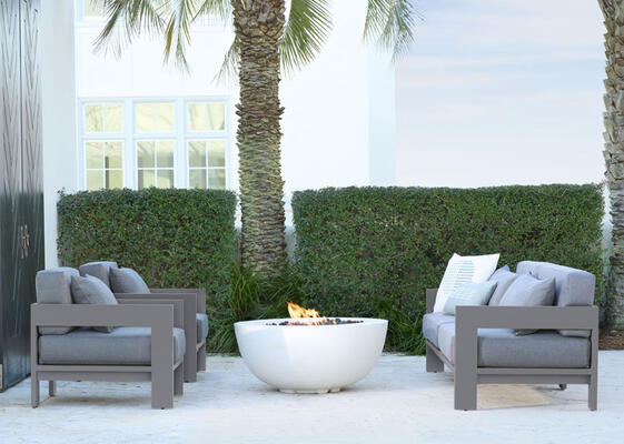Jupiter sofa and lounge chairs shown in Zinc hand-cast aluminum with Graphite performance basket-weave cushions surround the Tulum bowl firepit in Bone finish. Seating also available in natural teak