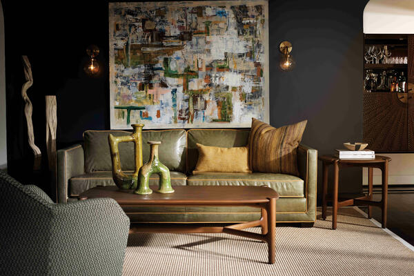 A nod to the beloved tuxedo sofa of the 1920s, the Raine is a modern-day gem with historical roots. Offered in a variety of leather and fabric options, including this rich olive green, the collection gives you the freedom to express your own personality through endless combinations of welts to choose from. A classic silhouette, the Raine intentionally positions the arms and back at the same height. Featuring contrast welting in all the right places, it celebrates and accentuates a continuous line of impeccable tailoring, much as bespoke suiting does.

Pairing perfectly with the Raine sofa, the Harlow collection comprises coffee tables, side tables and a console in solid mahogany wood with a warm chestnut stain. Smooth as butter in an elegant matte finish, these midcentury-modern-inspired pieces are constructed with curved trestle bases intentionally designed so that the legs meet the table right where they are 