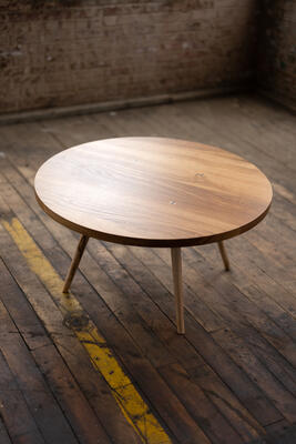 The round Velma coffee table gives a nod of respect to midcentury modern– inspired design and craft. Its sleek maple legs are hand-turned on the lathe. Discreet walnut details combine with the expressive grain of urban wood to invite a clean and contemporary silhouette into your interior design.