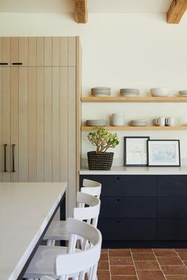 A kitchen in Montecito with DeVol cabinetry, vintage ceiling beams and terra cotta flooring.