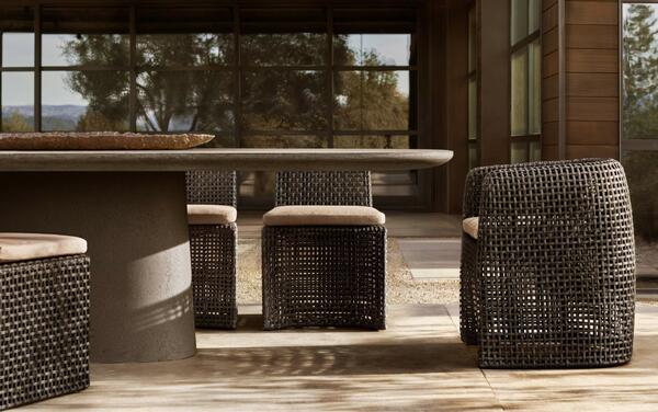 Gemini dining seating in all-weather wicker shown with the Caprera concrete dining table