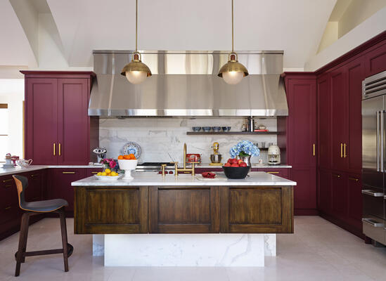A dull, khaki colored kitchen was transformed with custom pendants, new faucets, hardware and a bold wine-colored cabinetry finish.

Our clients’ kitchen, formerly a drab green-grey, was transformed and enlivened with a custom purple-red satin and walnut faux finish. Faucets and hardware were replaced with a bold brushed bronze, while lighting from a Long Island-based workshop beautifully caps it all off. 