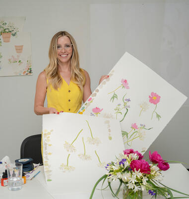 Watercolor artist Caitlin McGauley poses with a few of her original watercolor paintings