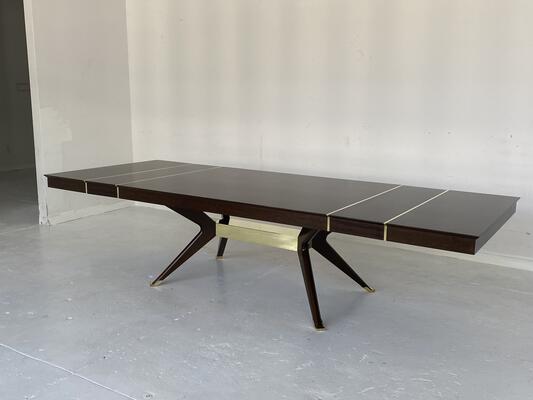 A custom modernist dining table shown with two additional leaves and brass detail