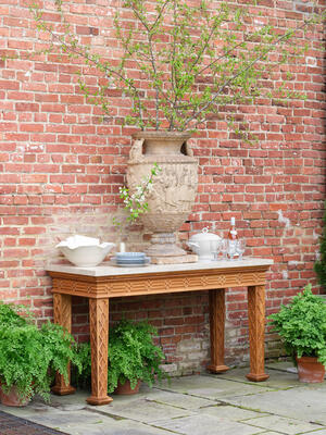 Our outdoor Howard console, made of sustainably sourced teak, features a honed light-marble top. 