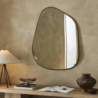 Hand-forged iron with a deep brass finish showcases the fluid, asymmetrical curves of the Nova mirror