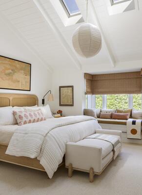 A primary bedroom features a caned bed frame,  and a modern but timeless sensibility.