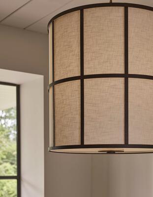 The natural linen shade of the Ashmore shade lantern is encased by a cage hand-finished in rust-effect paint