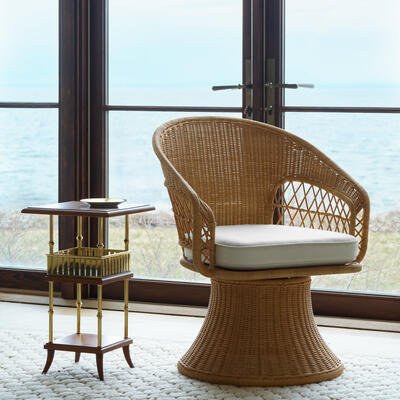 The Amelia petite swivel chair features a flared drum base and open lattice wickerwork