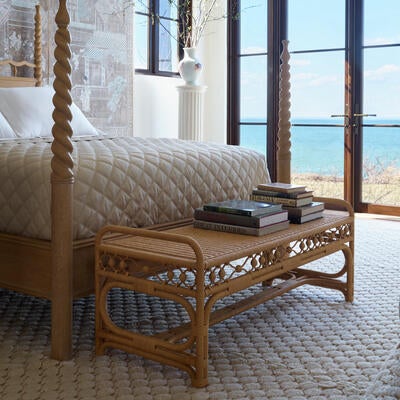 The Carlisle bench is woven from natural rattan with an intricate apron of interlocking rings