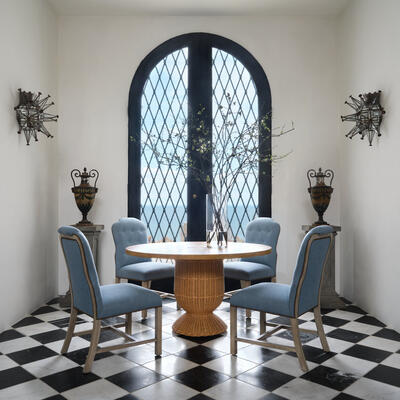 The Braided Urn dining table features a gracefully curved rattan base