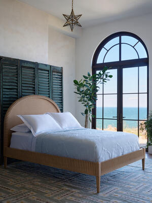 The Winchester bed features a gracefully curved headboard framed in oak with cane paneling