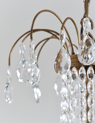 Conholt chandelier: Glass droplets fall gracefully from the brass frame, radiating refracted light
