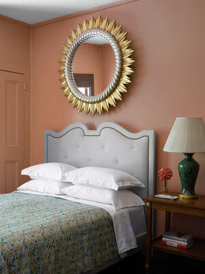 A brilliant gold sunburst frame surrounds the new Aurora mirror, shown here hanging above the Williams bed