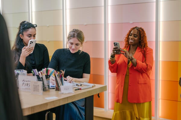 Artist Deanna First draws portraits while design ambassador Delia Kenza looks on