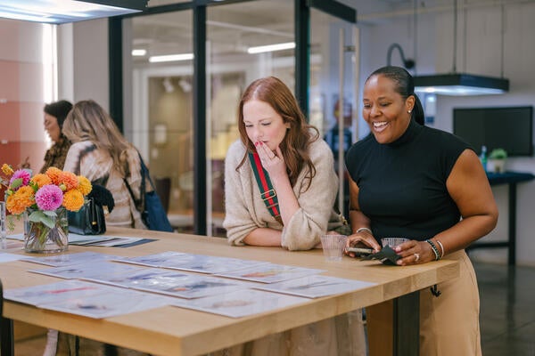 Melissa Oholendt and Kelly Collier-Clark admire completed portraits of their fellow design ambassadors