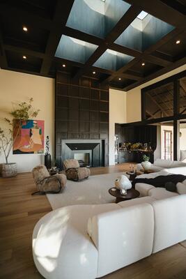 A sprawling Arhaus sectional strikes a dramatic contrast with a dark-paneled fireplace and coffered ceiling