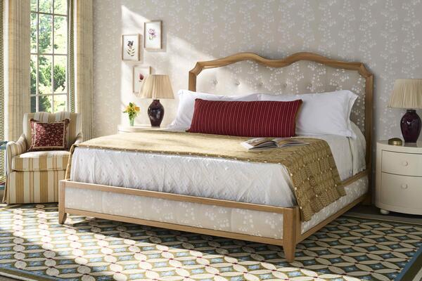 The Arthur oak bed pairs a structured wood frame with upholstered panels and subtle carved curves